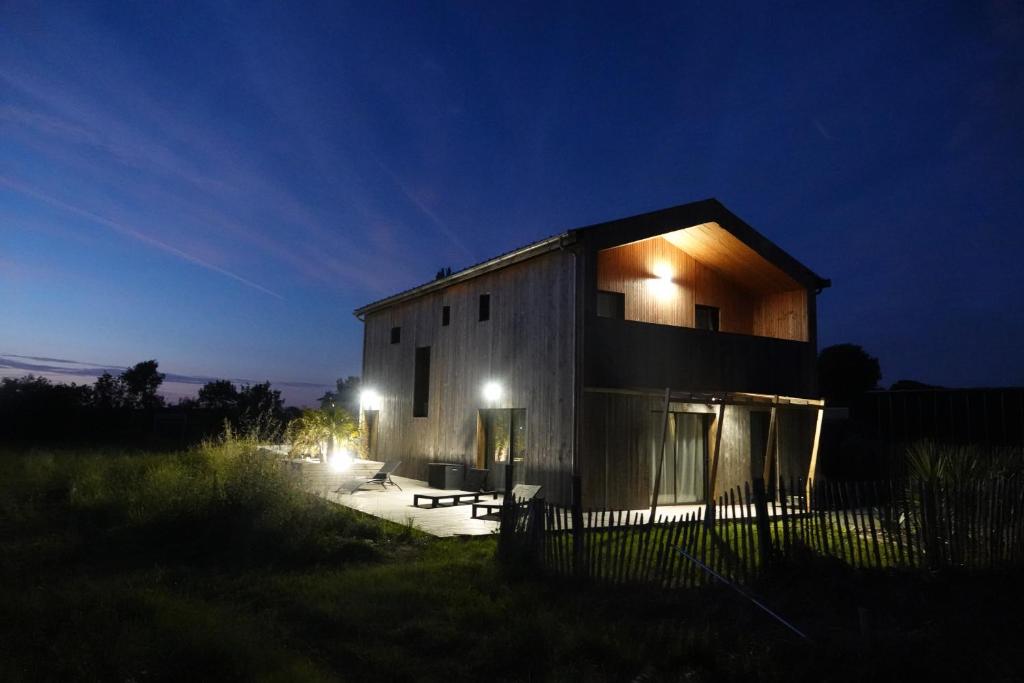 une maison avec des lumières sur son côté la nuit dans l'établissement Maison Bois, Les Conches 10 pers, à Longeville-sur-Mer