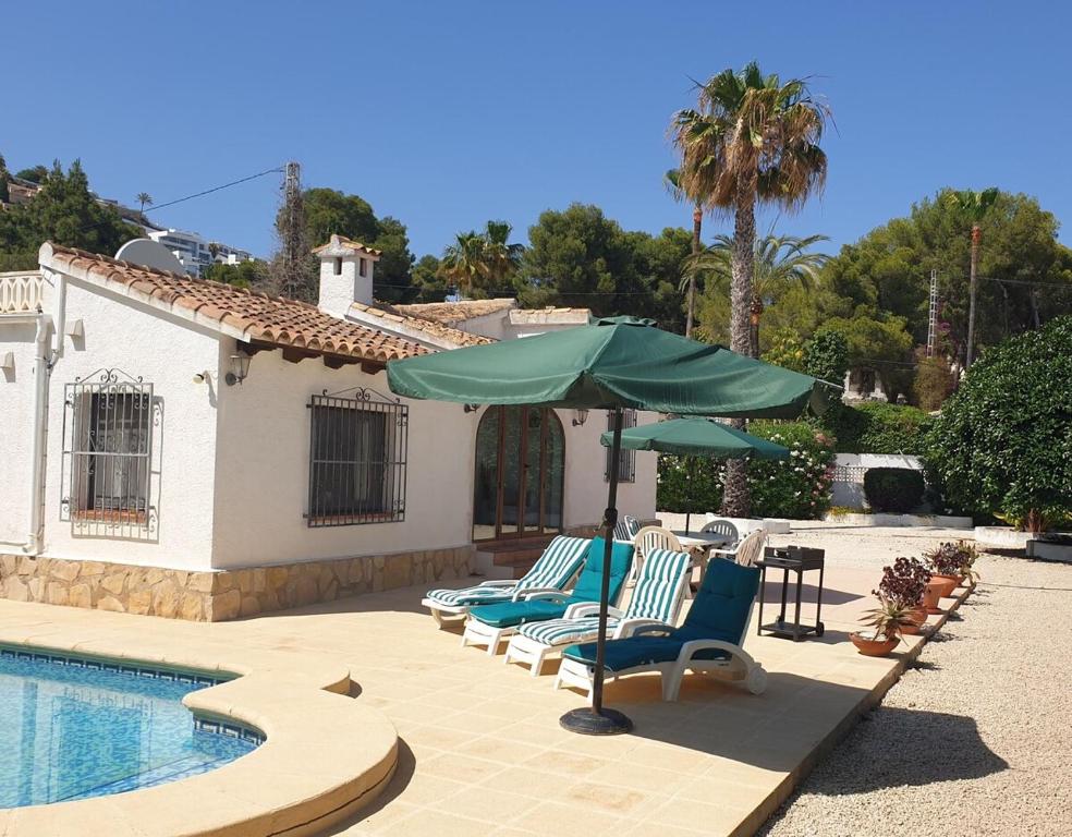 a group of chairs and an umbrella next to a pool at Villa Casa Nuestra in Moraira