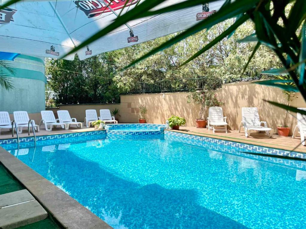 a swimming pool with white lounge chairs and a swimming pool at Europe Holiday Apartments First Sea Line Coast in Pomorie