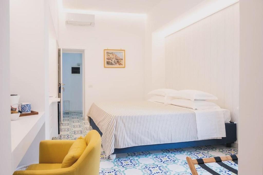 a white bedroom with a bed and a yellow chair at B&B L'Agapanto in Capri