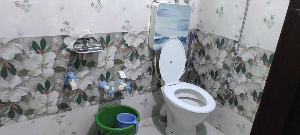 a bathroom with a toilet and flowers on the wall at OYO Home Homestay Manzoor Dedard in Pahalgām