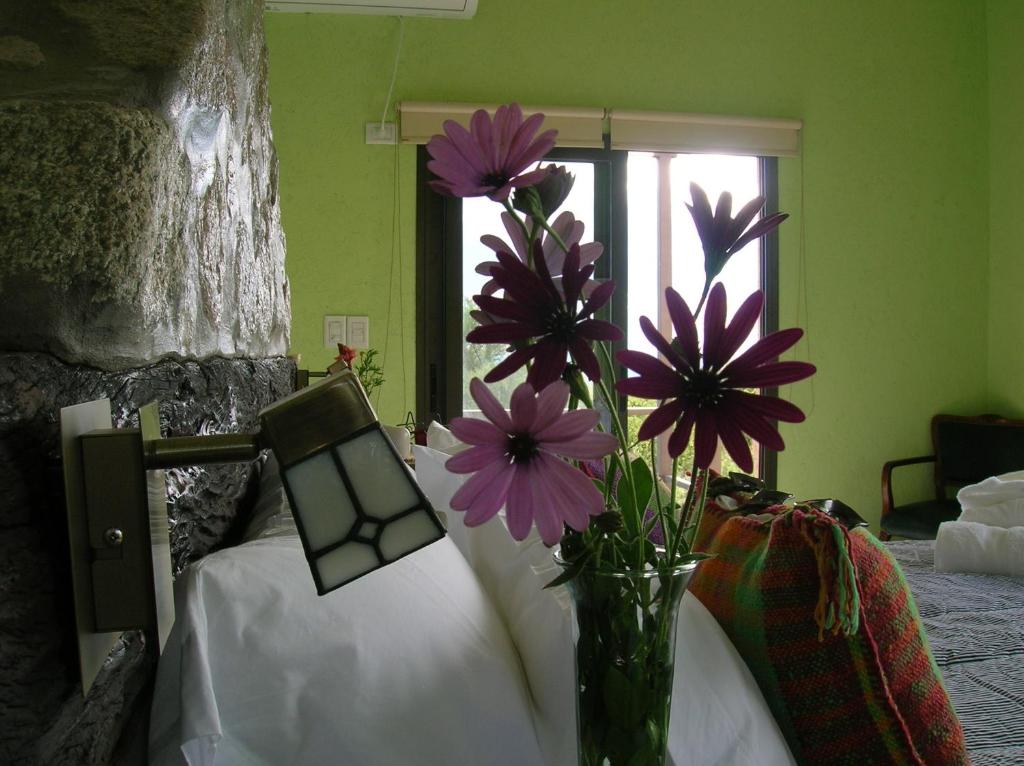 un jarrón lleno de flores púrpuras junto a una cama en Apart Los Antiguos en Merlo