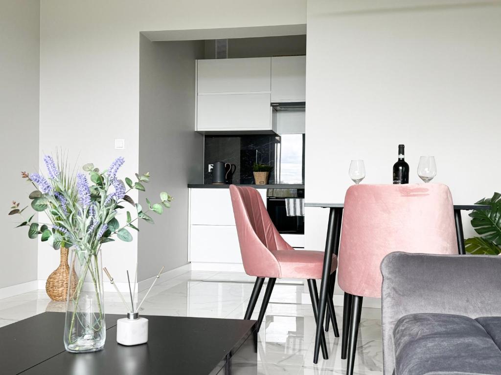 a living room with pink chairs and a table at Laguna Beskidów Resort - Apartament A74 in Zarzecze
