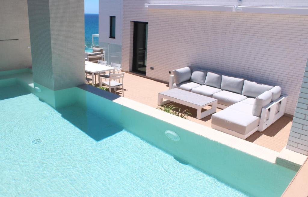 een woonkamer met een bank en een zwembad bij Luxury penthouse with private pool in El Campello
