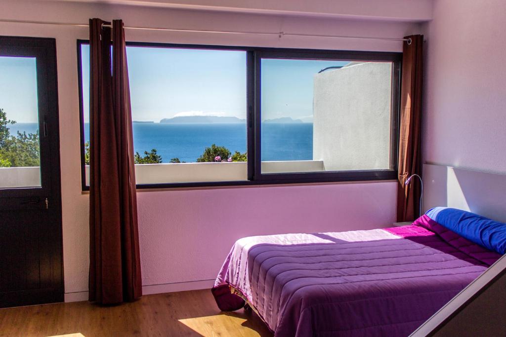 ein Schlafzimmer mit einem Bett und einem großen Fenster in der Unterkunft Apartamento Gois in Machico