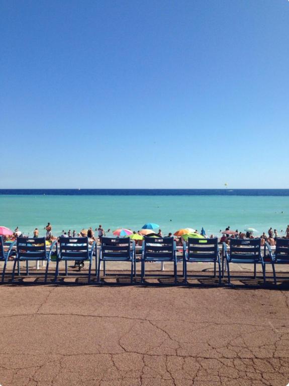 un groupe de personnes assises sur une plage avec des parasols dans l'établissement Charmant 3 pieces en bord de mer et proche tramway, à Nice