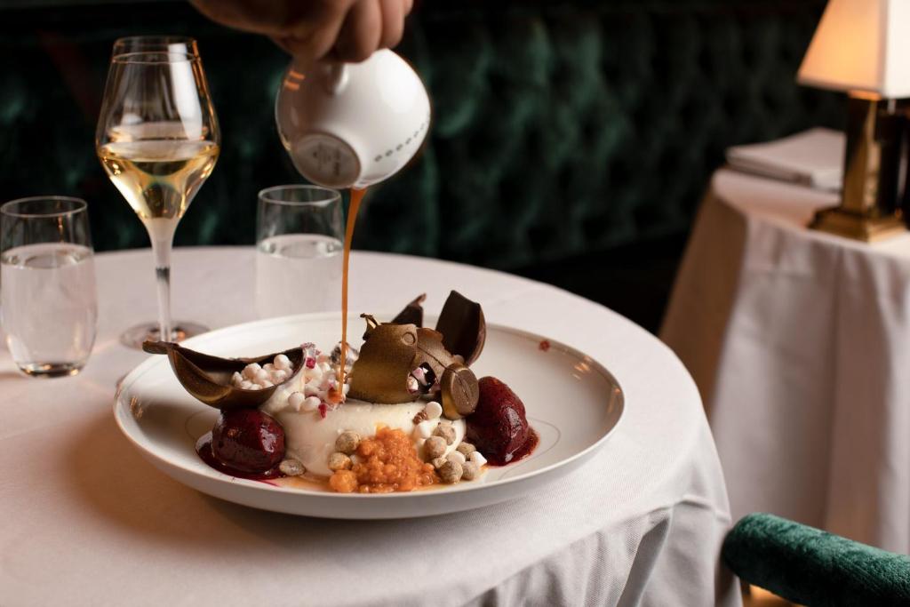 a plate of food on a table with a glass of wine at Bank Hotel, a Member of Small Luxury Hotels in Stockholm
