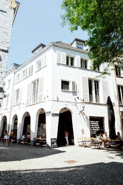 een wit gebouw waar mensen buiten zitten bij Boutique Hotel DARQ in Maastricht