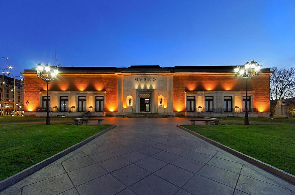 Un gran edificio de ladrillo con bancos delante. en LaSuiza, en Bilbao