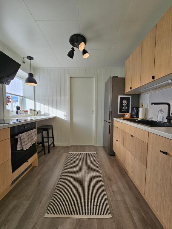 a kitchen with wooden cabinets and a stainless steel refrigerator at Bright and modern apartment with beautiful view in Hammerfest
