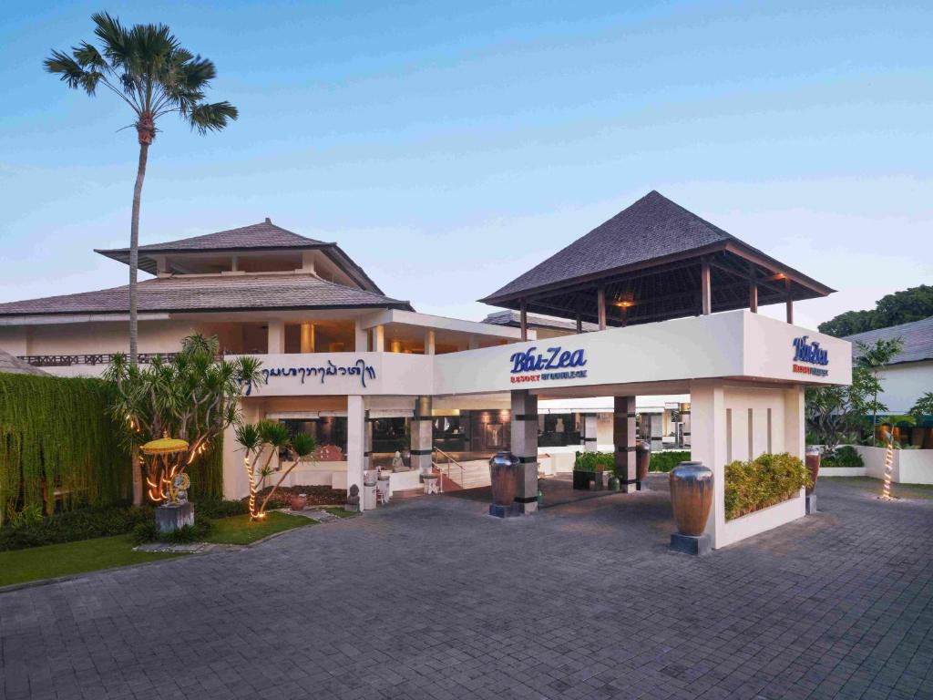 a building with a palm tree in front of it at Blu-Zea Resort by Double-Six in Seminyak