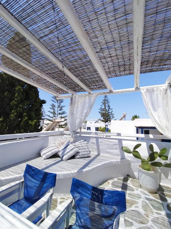 a patio with blue chairs under a white pergola at Angelina Greek House in Parikia