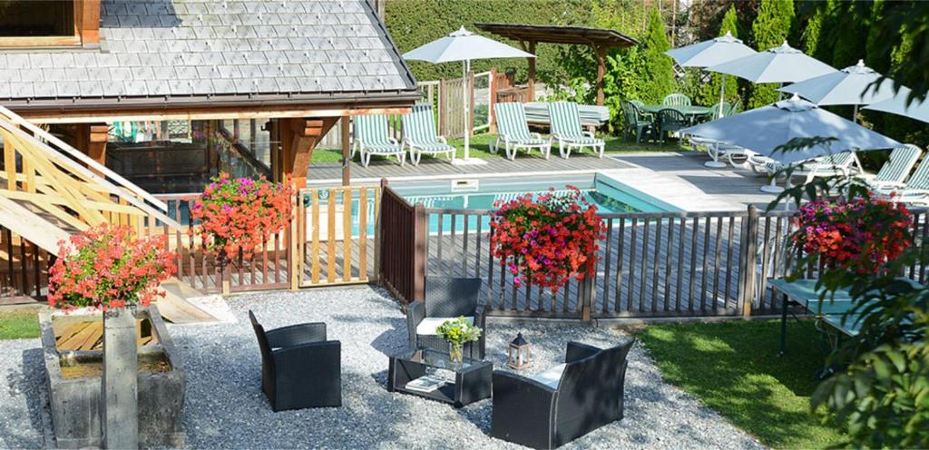 une cour avec une clôture et une piscine avec des chaises et des parasols dans l'établissement Le Morillon - Piscine et Spa, à Morillon