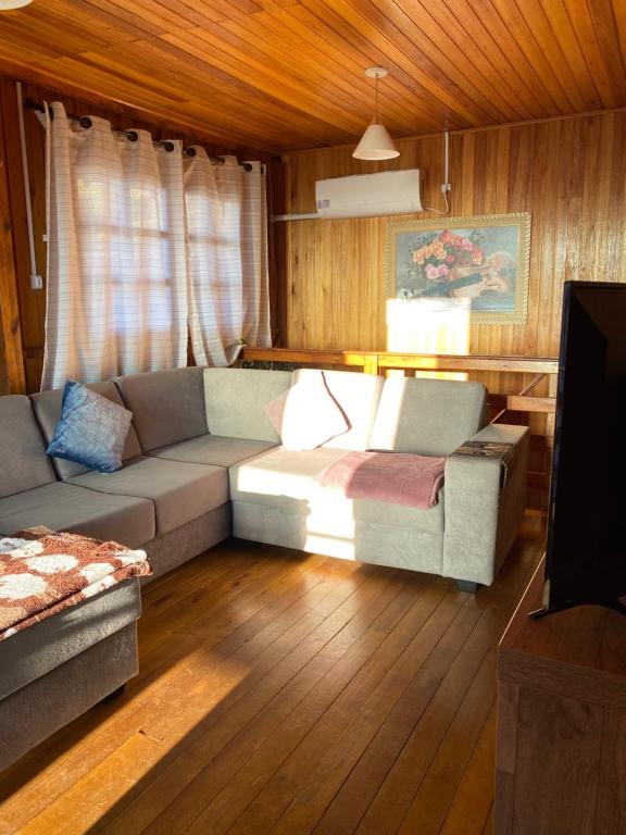 a living room with a couch and a tv at Chalé Boutique Recanto dos Ursos in São Joaquim