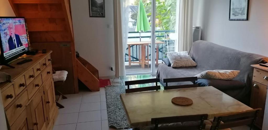 a living room with a couch and a table and a tv at Appartement cosy à Saint-Mamet - 36 m² - Vue montagne in Saint-Mamet