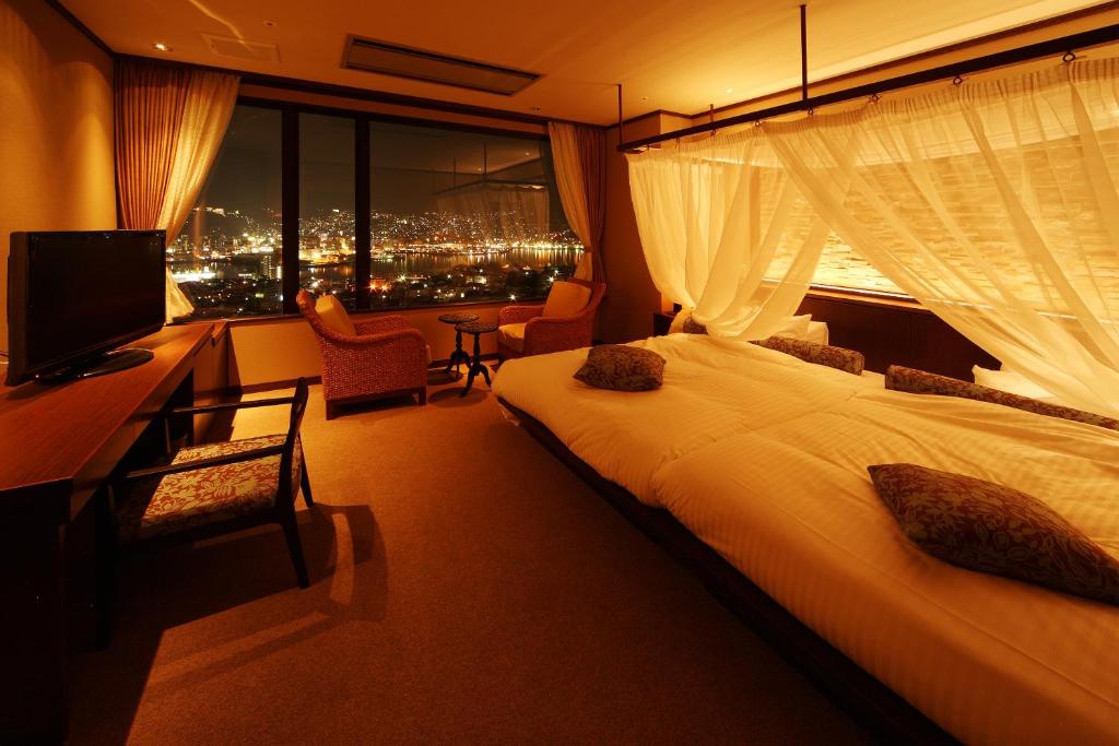 um quarto de hotel com uma cama grande e uma janela em Hotel Amandi em Nagasaki