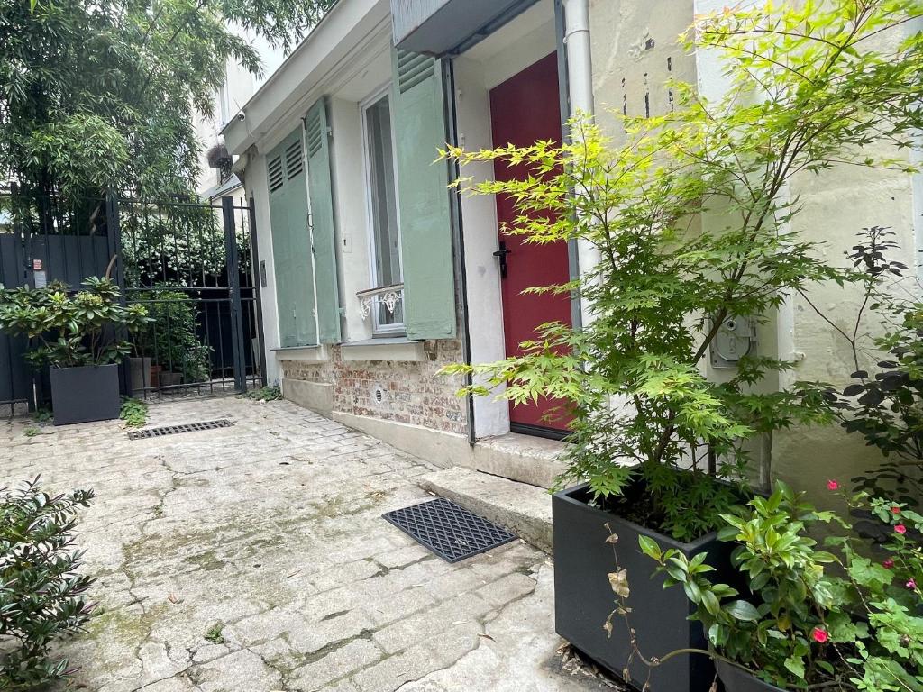 une maison avec une porte rouge et quelques plantes dans l'établissement Charmant et tranquille plein centre de Paris!, à Paris