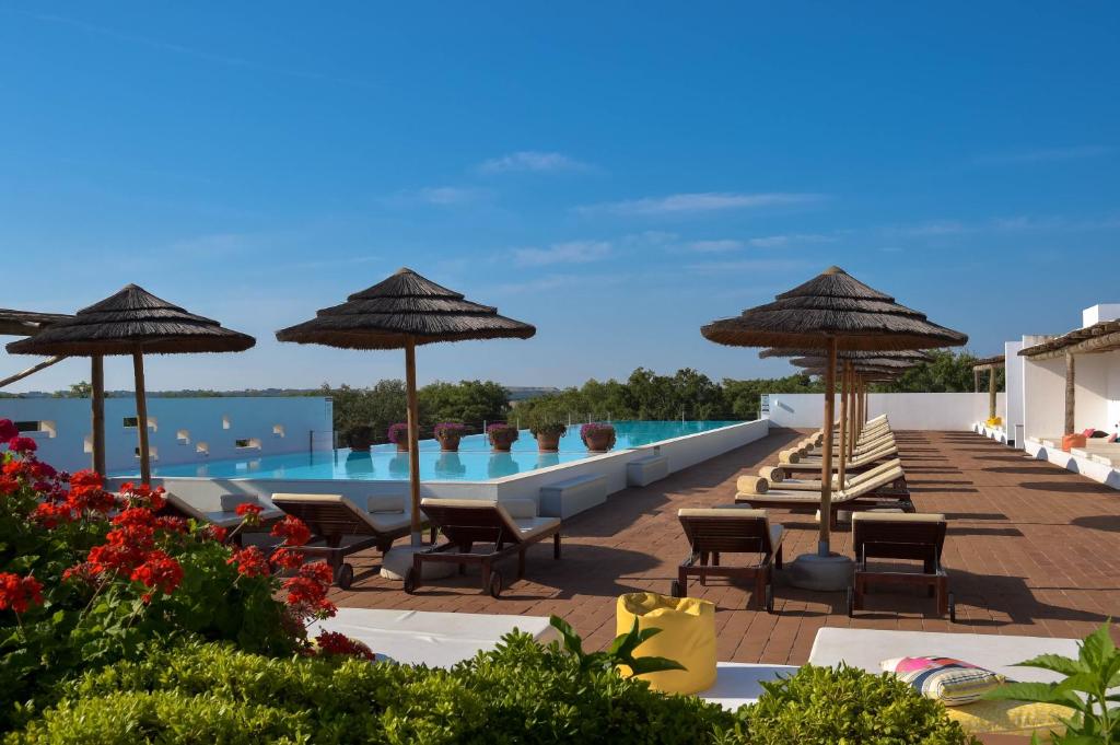 uma piscina num resort com cadeiras e guarda-sóis em The Lince Ecorkhotel Évora em Évora