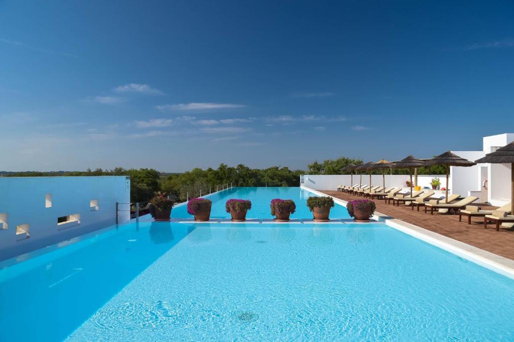uma grande piscina com água azul num edifício em The Lince Ecorkhotel Évora em Évora
