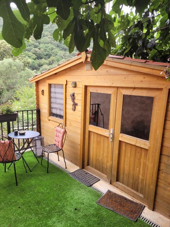 une cabane en bois avec une table, des chaises et un patio dans l'établissement Loue chalet de 11m2, à Auribeau-sur-Siagne