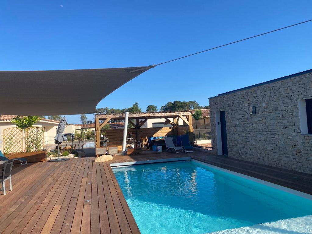- une piscine avec une terrasse en bois à côté d'un bâtiment dans l'établissement Villa standing Arciquadra Porto Vecchio, à Lecci