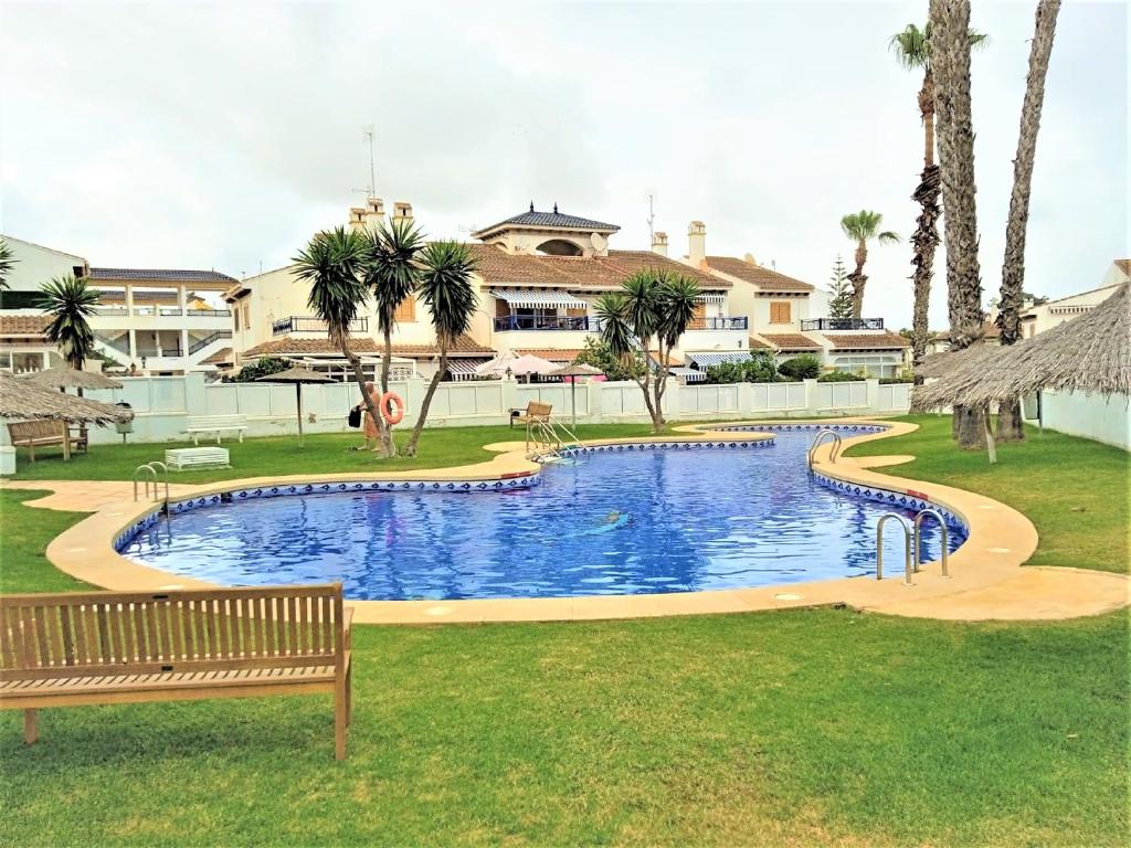 a swimming pool in a yard with a bench at Chalet adosado en RIOMAR-3, urbanización residencial privada in La Horadada