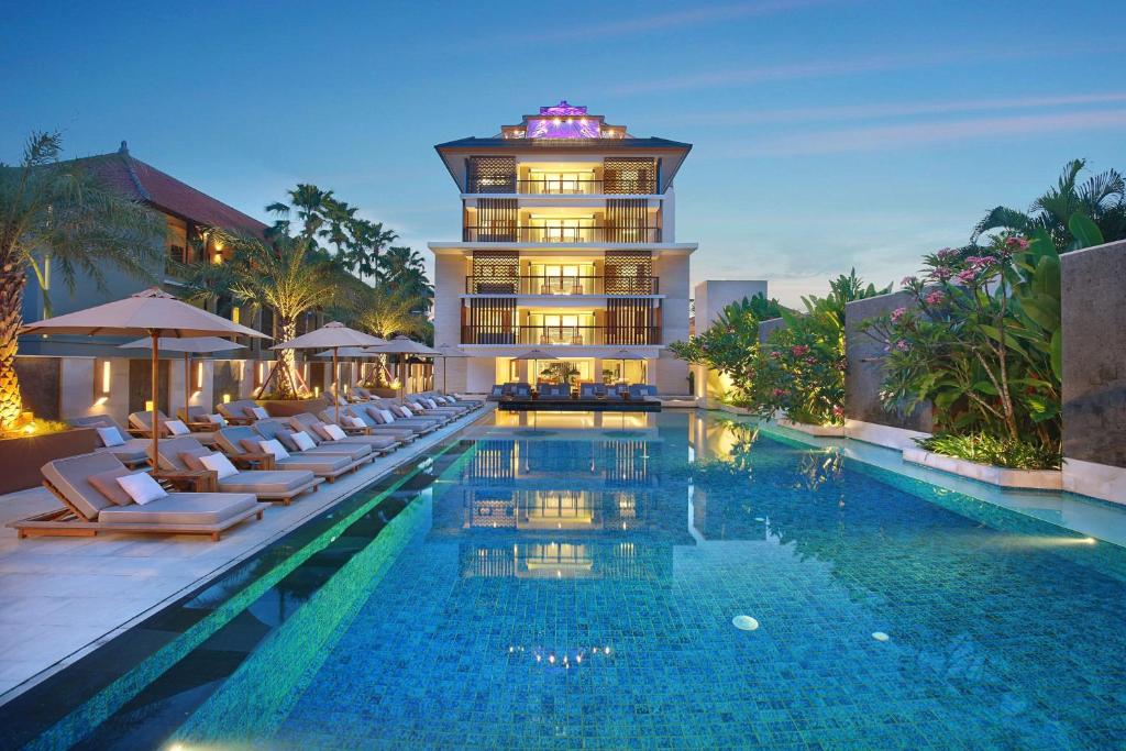a hotel with a swimming pool in front of a building at The Bandha Hotel & Suites in Legian