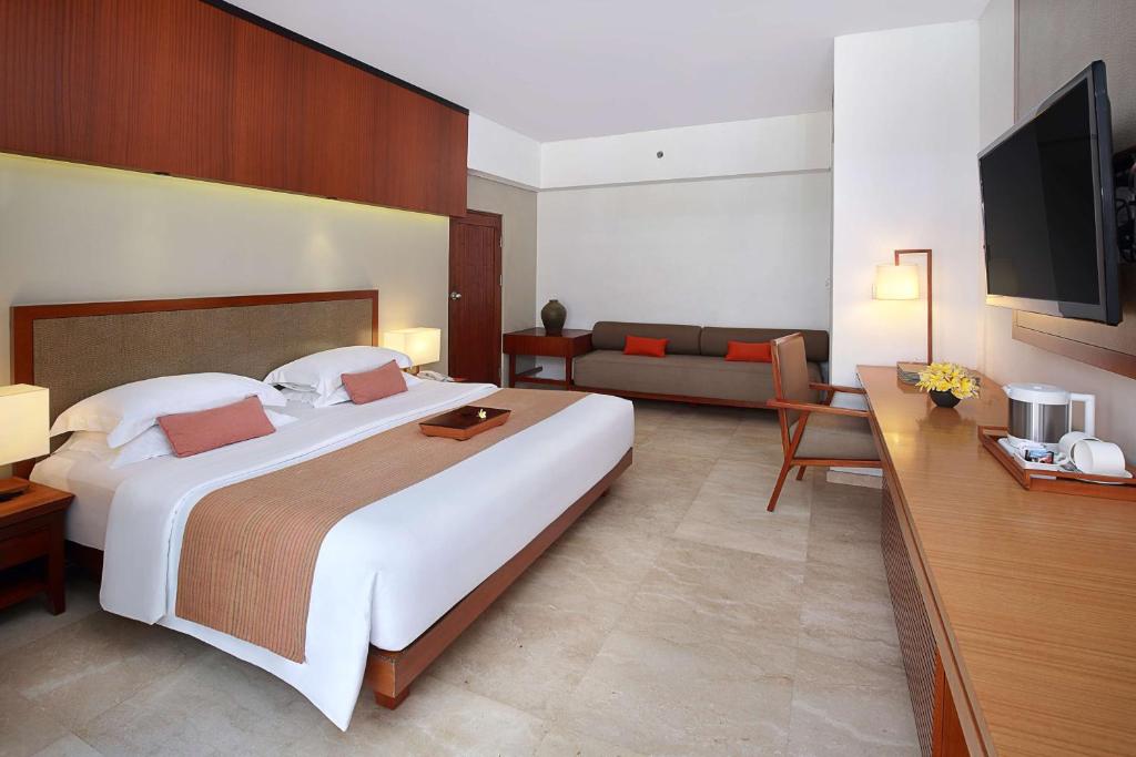 a hotel room with a large bed and a couch at The Magani Hotel and Spa in Legian
