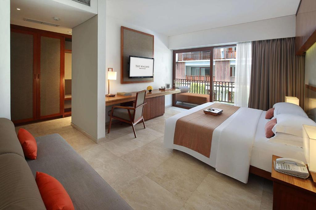 a hotel room with a large bed and a desk at The Magani Hotel and Spa in Legian
