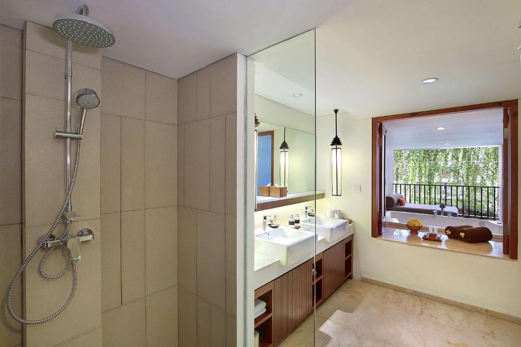 a bathroom with a shower and a sink and a mirror at The Magani Hotel and Spa in Legian