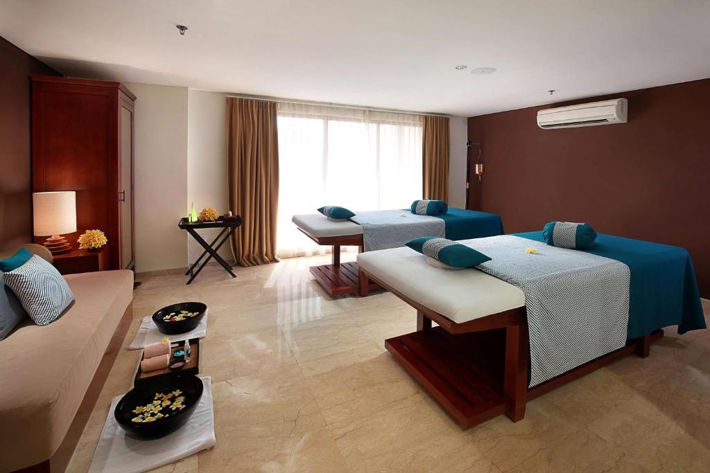 a hotel room with two beds and a living room at The Magani Hotel and Spa in Legian
