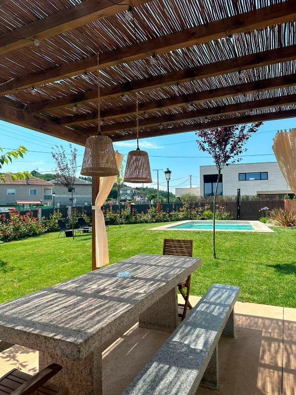 a picnic table under a wooden pergola with two lights at A Casa da Carminha, Ribeira Sacra in Pereiro de Aguiar
