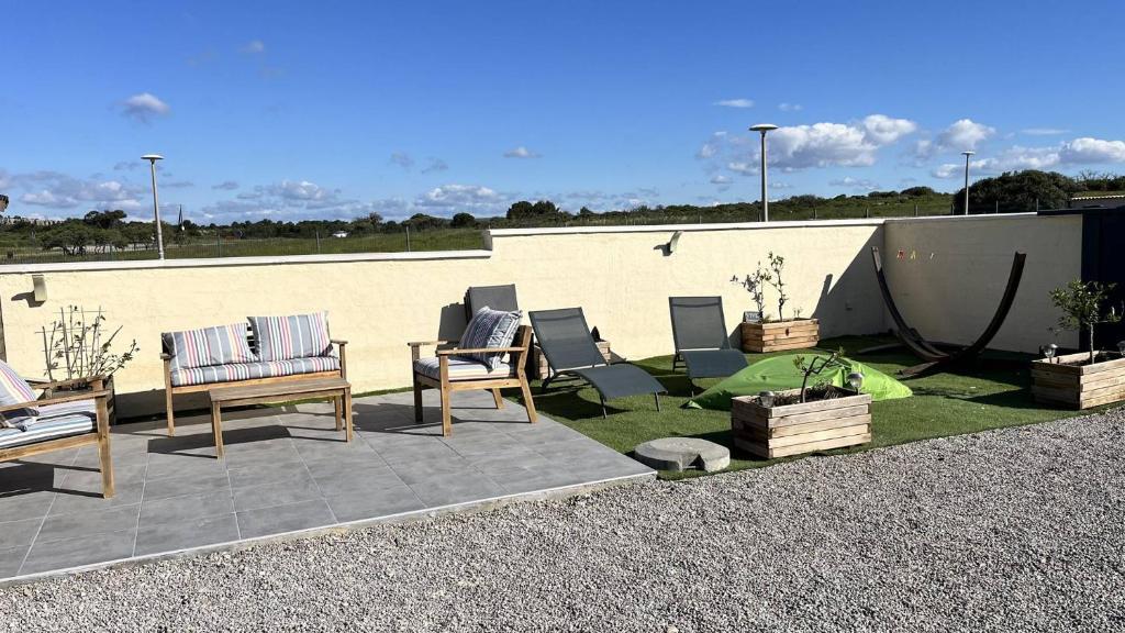 un groupe de chaises assises sur une terrasse dans l'établissement Pavillon climatisé avec extérieur et piscine collective - 4PAV87, à Saint Pierre La Mer