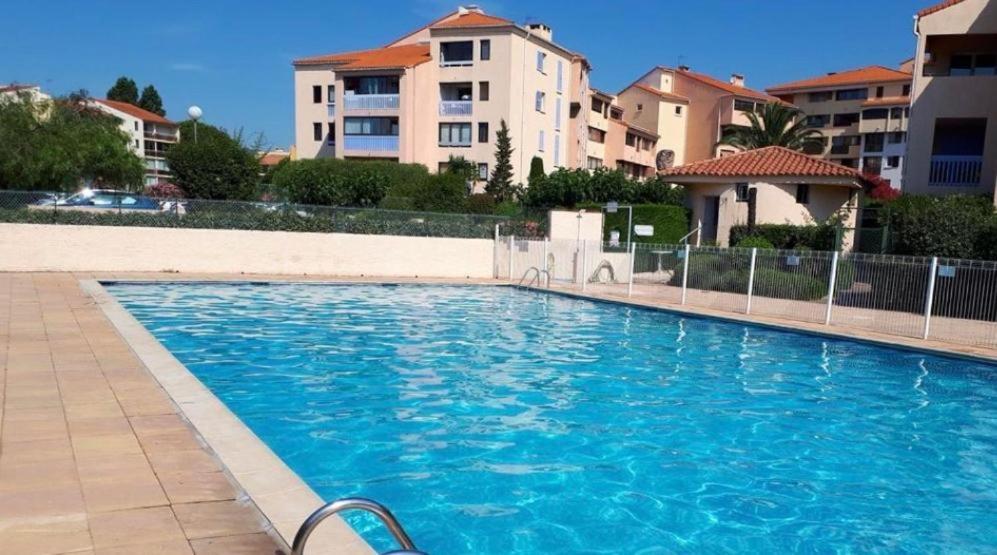 une piscine bleue avec des bâtiments en arrière-plan dans l'établissement Location T2, à Fréjus