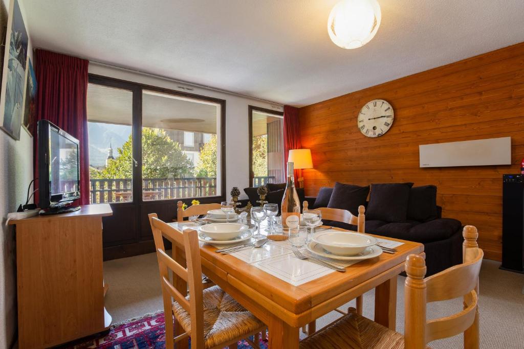 une salle à manger avec une table, des chaises et une horloge dans l'établissement Appartement Lachenal 209A - Happy Rentals, à Chamonix-Mont-Blanc