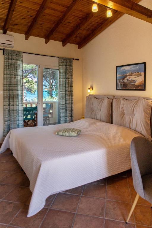 a bedroom with a large bed and a window at Elenas Beach Studios in Vourvourou