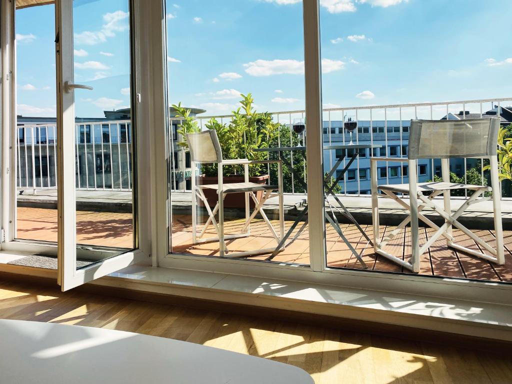 balcón con 2 sillas y vistas a un edificio en Victoria Apartments, en Düsseldorf