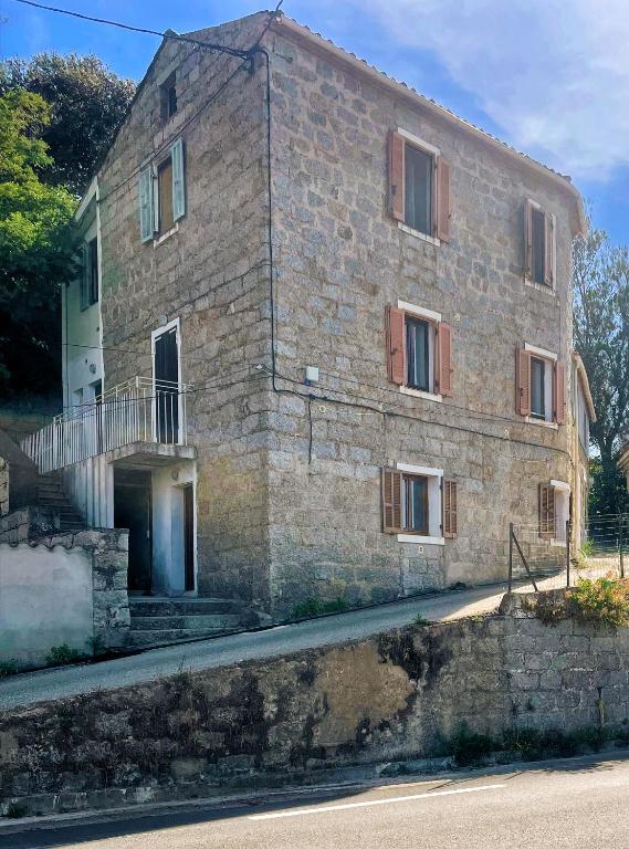 - un vieux bâtiment en pierre avec un balcon dans une rue dans l'établissement Appartement Sartène 2 personnes, à Sartène