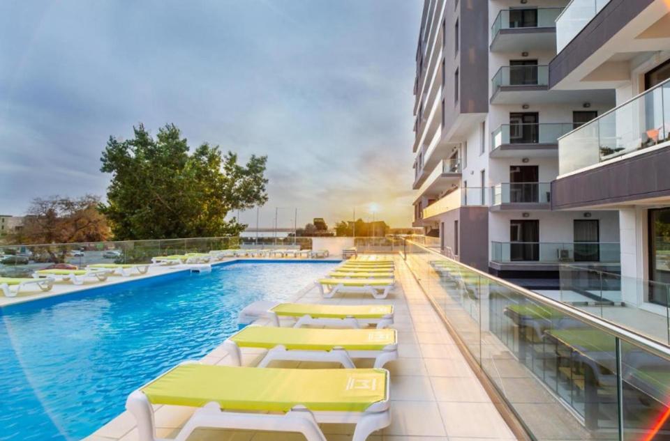 a swimming pool with lounge chairs and a building at Luxury relax Mamaia Nord in Năvodari
