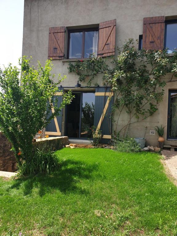 une maison avec une pelouse verte devant elle dans l'établissement Charmante maison de famille près de Lyon, à Lozanne
