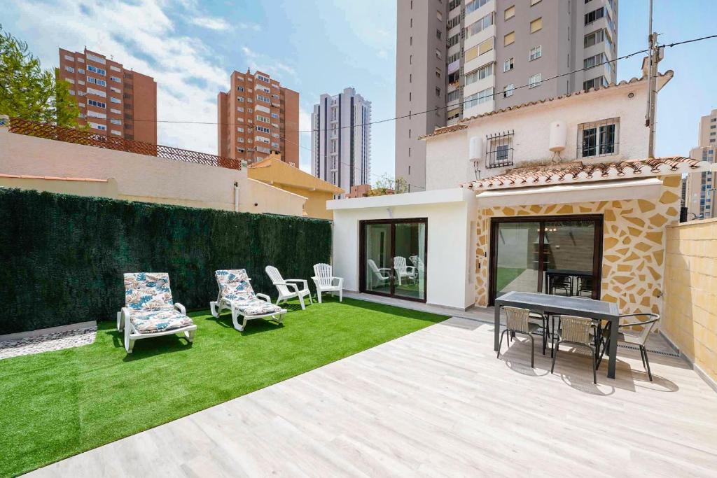 a patio with a table and chairs on a lawn at Casa LOMA con terreno privado y parking compartido - a 800m de Playa Poniente in Benidorm