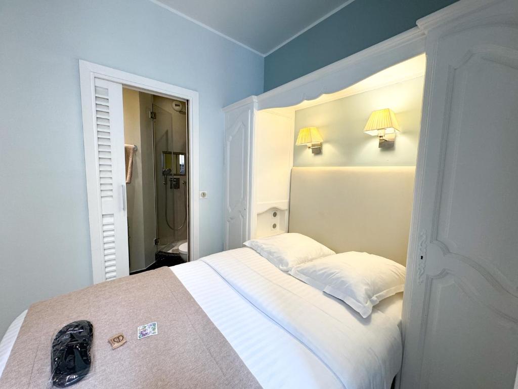 a bedroom with a white bed with two pillows at Hôtel de Provence in Cannes