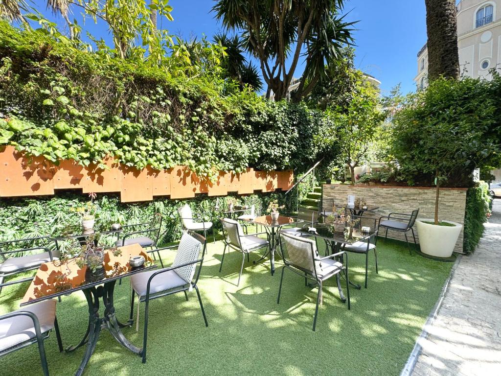 a patio with tables and chairs on the grass at Hôtel de Provence in Cannes