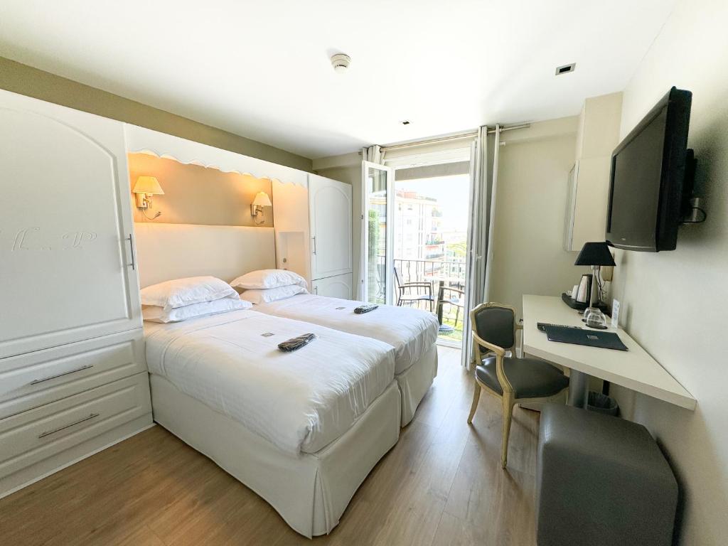 a bedroom with a bed and a desk and a television at Hôtel de Provence in Cannes