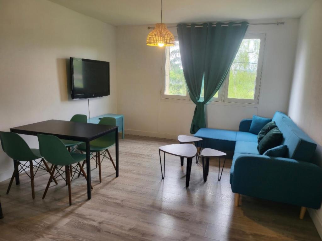 a living room with a blue couch and a table at Appartement Clermont-Ferrand F3 2 chambres 1 chambre avec 1 lit simple et 1 chambre avec 2 lits doubles in Clermont-Ferrand