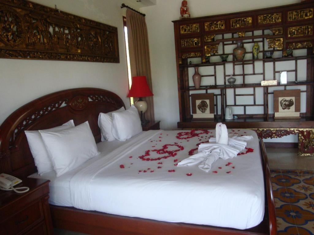 - une chambre avec un lit orné de fleurs rouges dans l'établissement Aqua Octaviana Bali Villa, à Canggu