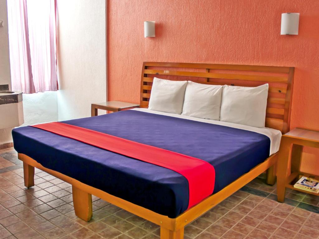 1 dormitorio con 1 cama con manta azul y roja en Hotel Soberanis, en Cancún