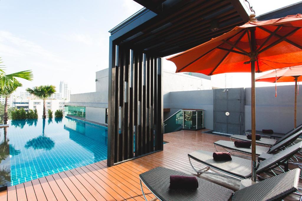 A rooftop pool deck with loungers and orange umbrellas.
