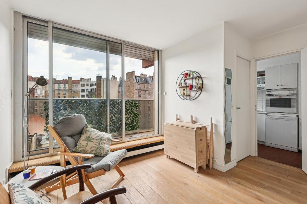 un salon avec un canapé et une grande fenêtre dans l'établissement Appartement calme et lumineux Place d'Italie by Weekome, à Paris