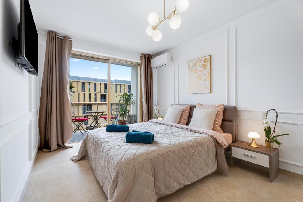 une chambre avec un lit et une grande fenêtre dans l'établissement Studio elegant avec balcon proche Mer et Tramway, à Nice